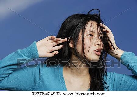 Stock Image - young lady glancing sideway, hands on head. Fotosearch