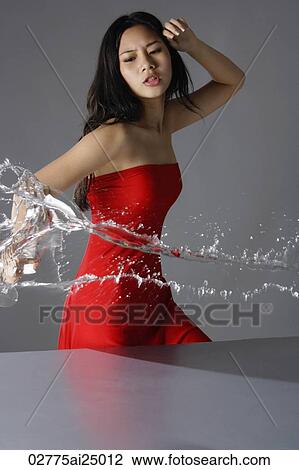 Stock Image - young lady in red, throwing liquid. Fotosearch