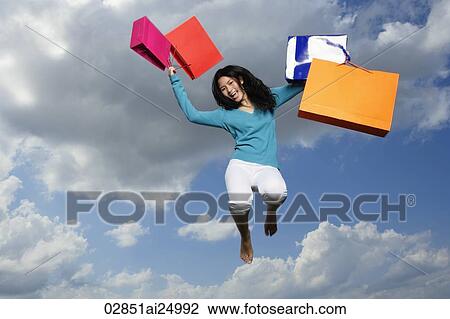 Stock Image - young lady jumping with shopping bags. Fotosearch