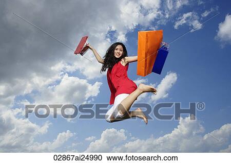 Stock Image - young lady jumping with shopping bags. Fotosearch