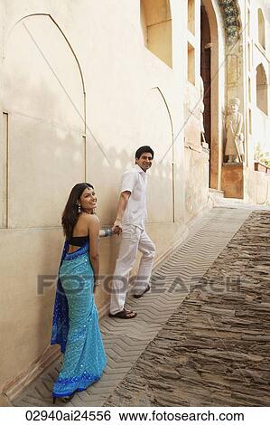 Stock Photograph - young man holding woman's hand, walking up a slope, woman in sari. Fotosearch