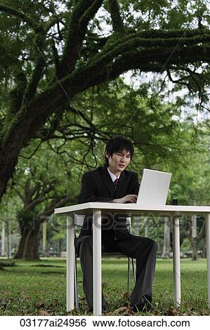 Stock Photograph - young man in suit, using laptop at a park. Fotosearch