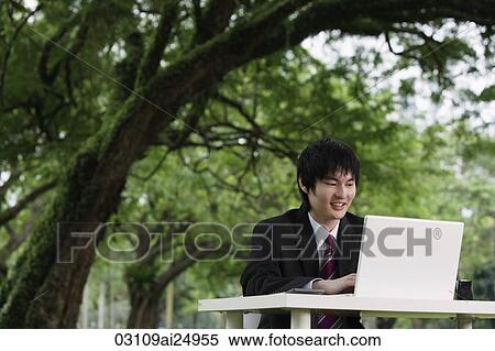young man in suit, using laptop outdoors View Large Photo Image Stock Photography - young man in suit, using laptop outdoors. Fotosearch