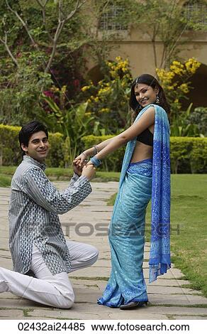 young man kneeling to propose to young woman in garden View Large Photo Image Stock Photography - young man kneeling to propose to young woman in garden. Fotosearch