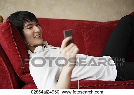 young man laying on sofa, MP3 player View Large Photo Image Stock Image - young man laying on sofa, MP3 player. Fotosearch