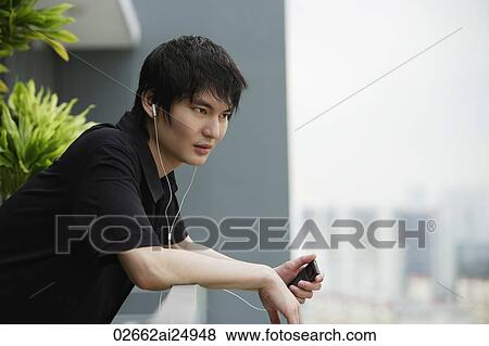 young man listening to MP3, on balcony View Large Photo Image Stock Photo - young man listening to MP3, on balcony. Fotosearch