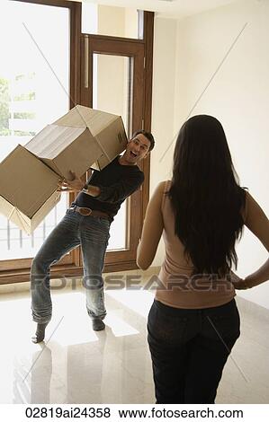 Stock Photo - young man try to impress woman with boxes in hands. Fotosearch