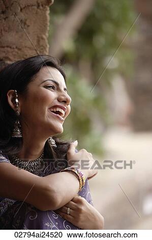 Stock Image - young woman in sari, big smile, arms around self. Fotosearch