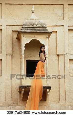 Stock Image - young woman in sari, on balcony. Fotosearch