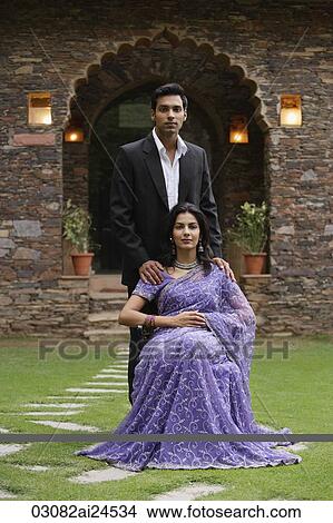 young woman in sari sitting with man standing for outdoor portrait View Large Photo Image Picture - young woman in sari sitting with man standing for outdoor portrait. Fotosearch