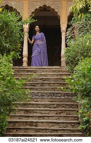 Stock Image - young woman in sari, standing at top of stairs. Fotosearch