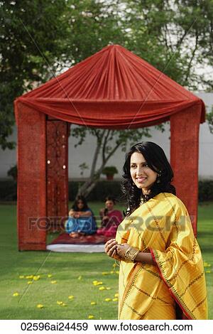 Stock Photo - young woman in yellow sari, in front of tent, two women in tent. Fotosearch