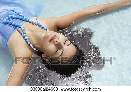 Stock Photo - young woman lying face up in pool. Fotosearch