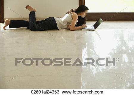 Stock Image - young woman on floor using computer. Fotosearch