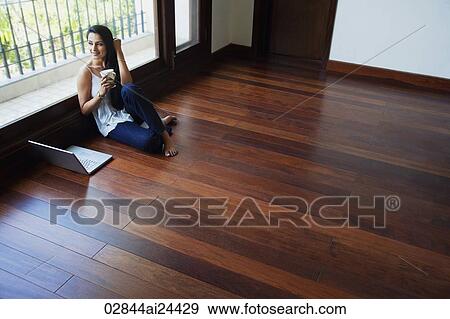young woman sitting on floor, coffee in hand, laptop View Large Photo Image Stock Photo - young woman sitting on floor, coffee in hand, laptop. Fotosearch