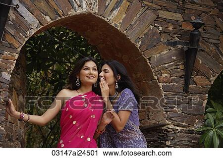 Stock Image - young women in saris, sharing secret. Fotosearch