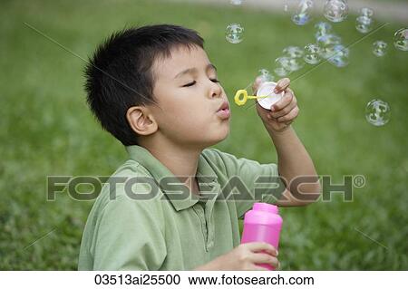 Stock Image - Boy blowing bubbles. Fotosearch
