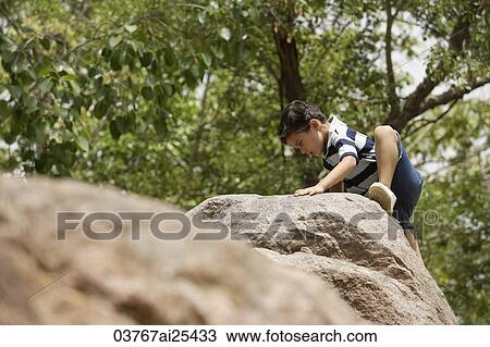 Stock Image - boy climbing on rocks. Fotosearch