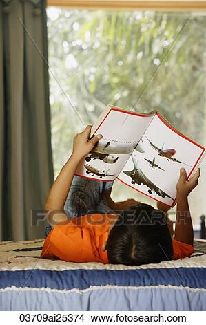 Picture - boy reading on bed. Fotosearch