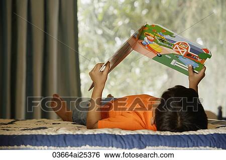 Stock Photograph - boy reading on bed. Fotosearch