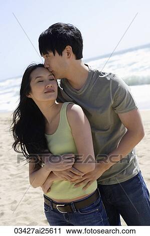 Stock Image - Couple embracing on beach. Fotosearch