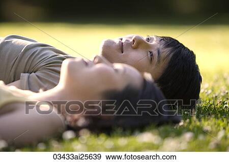 Couple lying in grass at park View Large Photo Image Stock Photo - Couple lying in grass at park. Fotosearch