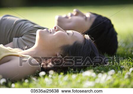 Stock Photo - Couple lying in grass at park. Fotosearch