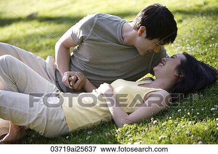 Couple lying in grass at park View Large Photo Image Stock Photo - Couple lying in grass at park. Fotosearch