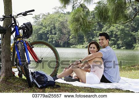 Couple resting by a lake View Large Photo Image Stock Photo - Couple resting by a lake. Fotosearch