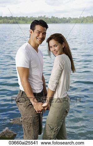Couple standing hand in hand near lake View Large Photo Image Stock Image - Couple standing hand in hand near lake. Fotosearch