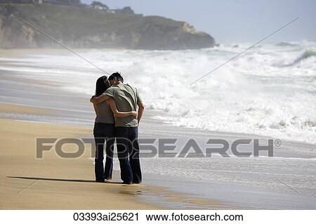 Stock Image - Couple standing on beach. Fotosearch