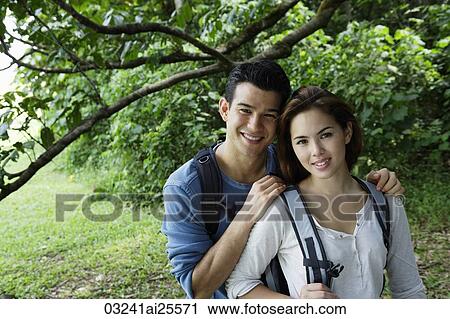 Couple with back packs standing under a tree View Large Photo Image Stock Image - Couple with back packs standing under a tree. Fotosearch