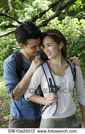 Couple with back packs standing under a tree View Large Photo Image Stock Image - Couple with back packs standing under a tree. Fotosearch