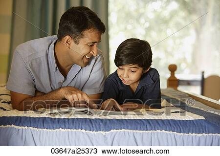 Stock Image - father and son reading book on bed. Fotosearch
