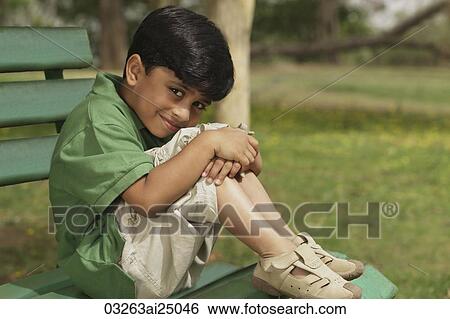 Stock Photograph - Little boy hugging knees on park bench. Fotosearch