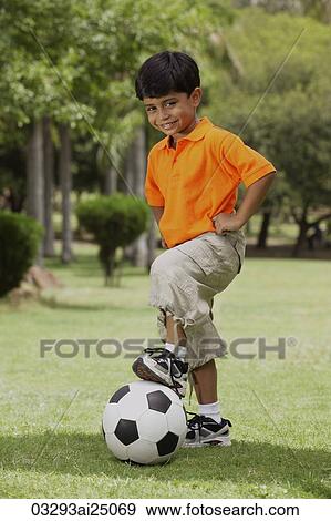 Stock Photo - little boy with foot on soccer ball. Fotosearch
