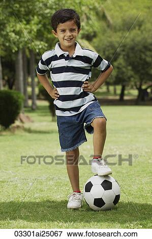 Stock Photo - little boy with foot on soccer ball. Fotosearch