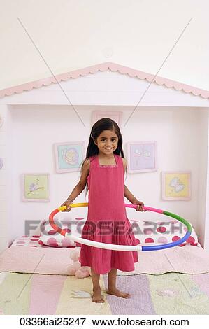 Stock Photo - little girl on bed with hula hoop. Fotosearch