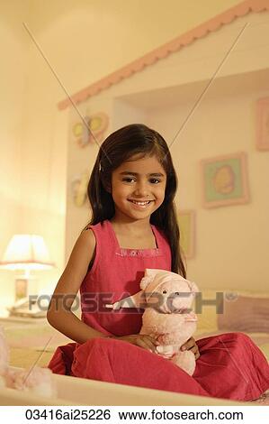Stock Photograph - little girl on bed with teddy bear. Fotosearch