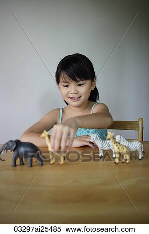 Stock Photography - Little girl playing with plastic animals. Fotosearch