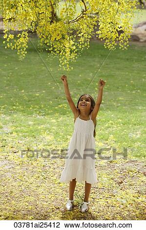 Stock Image - little girl reaching up to tree. Fotosearch