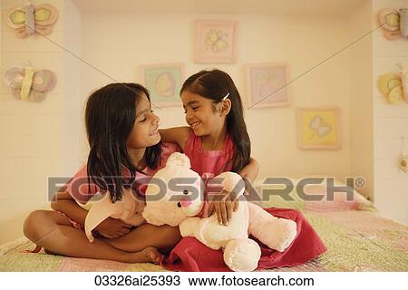 Stock Image - little girls with stuff bears on bed. Fotosearch