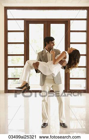 Stock Image - man carrying woman over threshold into empty home. Fotosearch