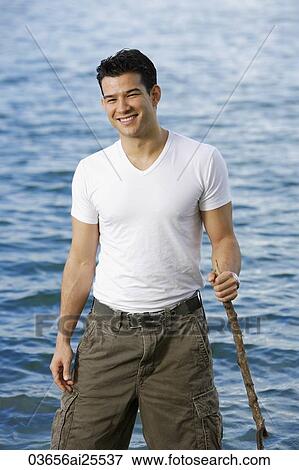 Man standing in lake, holding stick View Large Photo Image Stock Photo - Man standing in lake, holding stick. Fotosearch