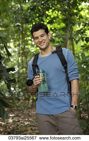 Man wearing a backpack, holding water bottle View Large Photo Image Stock Photo - Man wearing a backpack, holding water bottle. Fotosearch