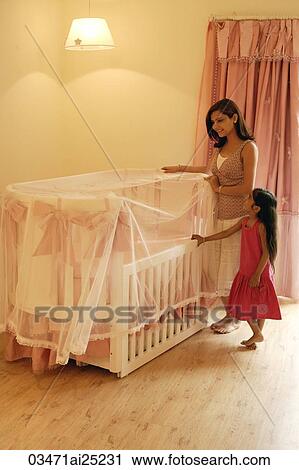 Stock Image - mother and daughter at side of crib. Fotosearch