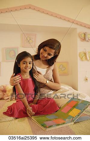 Stock Photography - mother and daughter reading book on bed. Fotosearch