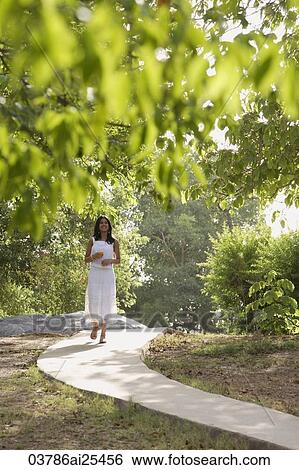 Stock Photograph - teen girl walking on path through park. Fotosearch