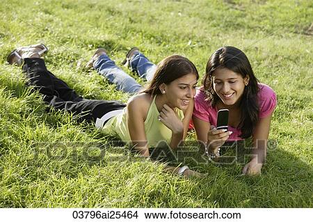 two teen girls in park, looking at text messages View Large Photo Image Picture - two teen girls in park, looking at text messages. Fotosearch