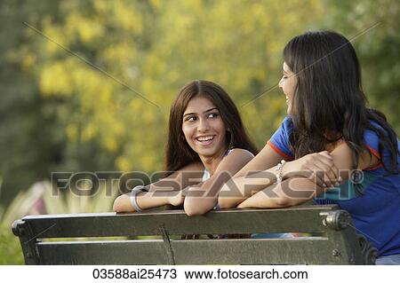 Stock Image - Two teen girls on park bench. Fotosearch